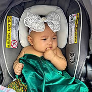 Celina joined the competition — help win amazing prizes! baby, child, car_seat, headband, bow, green_fabric, hand, face, infant, seat, blanket, cute, portrait, indoors, clothing, sitting, person, young_child, thoughtful, closeup