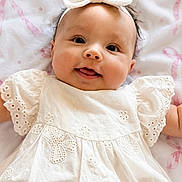 Elena joined the competition — help win amazing prizes! baby, infant, child, smiling, white_dress, headband, bow, blanket, pink_ribbons, cute, happy, portrait, close_up, indoor, soft_lighting, face, person, newborn, lying_down, adorable