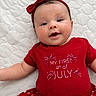 Elena is registered to the contest to win money with this photo: baby, infant, smiling, red_clothing, headband, face, cute, celebration, festive, toddler, lying_down, quilted_bedspread, holiday, stars, skirt, celebration_clothing, portrait, happy, cheerful, child