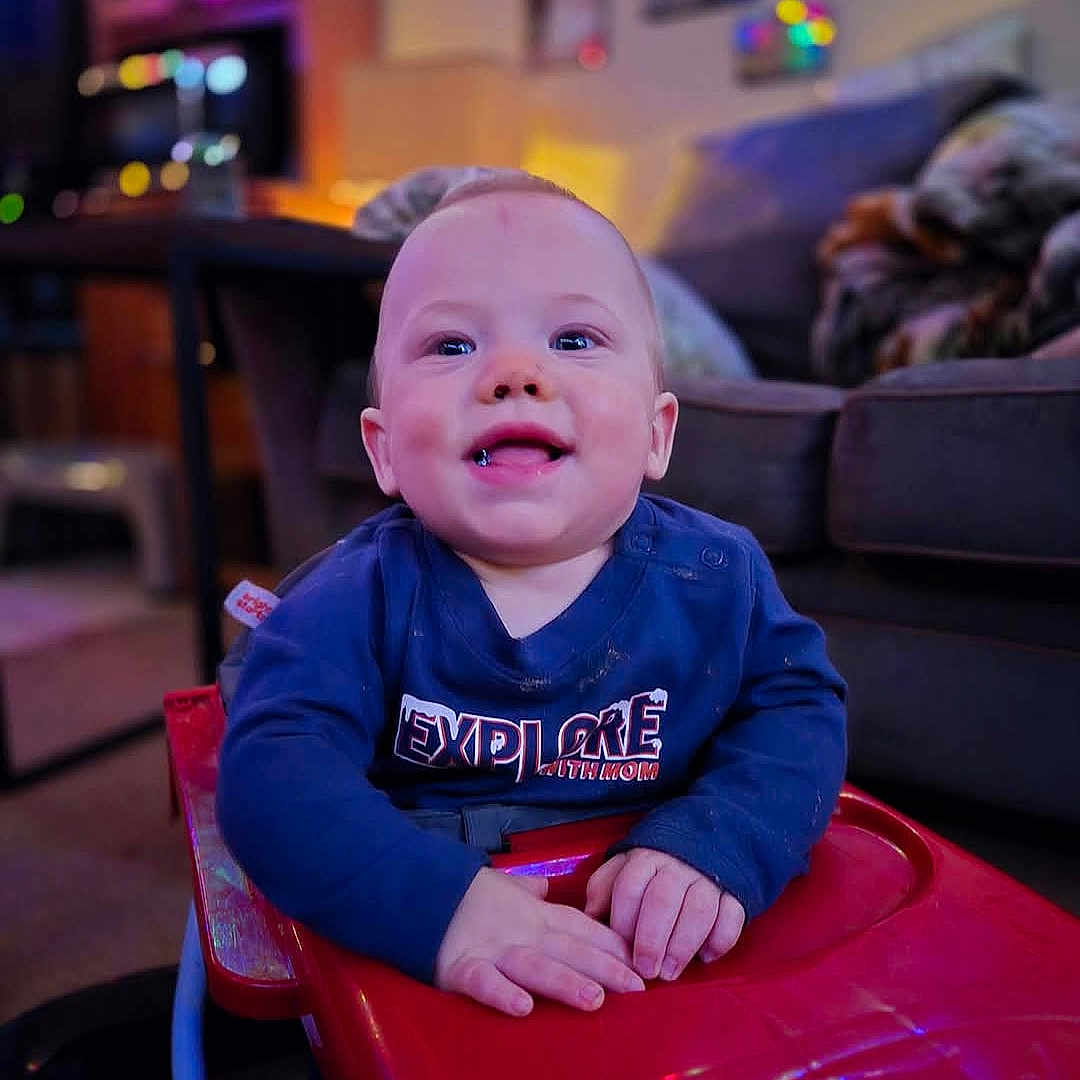 Roman is registered to the contest to win money with this photo: baby, babylaughing, clothing, coat, face, furniture, happy, head, jacket, laughing, lighting, person, photography, playarea, portrait, purple, sitting, smile, t_shirt, urban