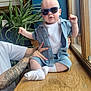 baby, child, sunglasses, blue_outfit, tattooed_arms, wooden_surface, window, plant, indoor, person, cute, fashion, casual, hands, sitting, infant, cool, portrait, light, home