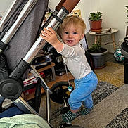 Elijah is registered to the contest to win money with this photo: bodypart, boy, child, clothing, e_scooter, face, finger, glove, hand, head, male, pants, person, photography, plant, portrait, pottedplant, stroller, transportation, vehicle