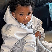 Rayne joined the competition — help win amazing prizes! toddler, child, curly_hair, white_sneakers, hoodie, sweatpants, carpet, rug, knitted_hat, living_room, couch, black_couch, earrings, indoor, casual_clothing, sitting, person, cute, young_child, curious