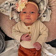 Cova is registered to the contest to win money with this photo: baby, infant, headband, flower, blanket, cozy, clothing, buttons, pants, cute, portrait, indoor, soft_lighting, baby_girl, lying_down, pink, cream, rust_color, child, newborn