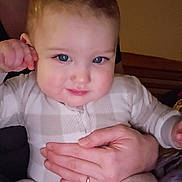 Mylo is registered to the contest to win money with this photo: adult, baby, blue_eyes, child, cozy, cute, expression, face, hand, head, holding, indoor, infant, outfit, person, plaid, portrait, seated, skin, warm