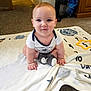 baby, child, infant, blanket, carpet, floor, sitting, smiling, cute, indoors, person, young, clothing, socks, playful, curious, hands, face, head, expression