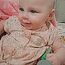 baby, infant, child, portrait, sitting, floral_outfit, pink_clothing, toy, colorful_toy, indoor, home, chair, pink_seat, face, eyes, bald_head, curious, cute, looking_away, cozy