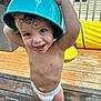 toddler, child, diaper, blue_bowl, hat, smiling, outdoor, wooden_deck, playful, happy, bare_chested, yellow_inflatable, summer, daylight, curly_hair, person, fun, cute, baby, backyard