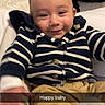 baby, smiling, striped_sweater, navy_blue, beige_pants, bed, pillow, white_bedding, infant, happy, motion_blur, child, portrait, indoor, cozy, cute, person, casual_clothing, closeup, young_child