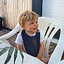 Charlie a rejoint le concours — aidez-le/la à gagner de superbes lots ! bib, blonde_hair, casual, child, daylight, happy, leaf_pattern, outdoor, pavement, plastic_chair, portrait, sitting, smiling, table, tablecloth, toddler, white_shirt, window_shutter, wooden_wall, young