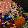 baby, child, colorful, cute, face, floor_mat, glowing_toy, happy, indoor, infant, pajamas, person, plastic_balls, playpen, playtime, plush_toys, seated, smiling, star_pattern, toy