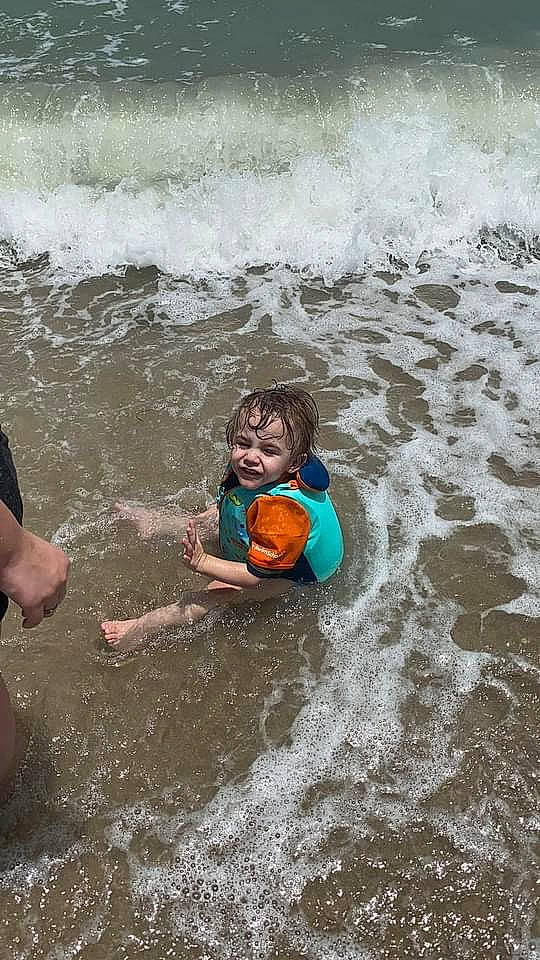 Jordon is registered to the contest to win money with this photo: beach, child, coast, fun, happy, leisure, ocean, people_on_beach, person, personal_protective_equipment, play, recreation, sand, shorts, smile, toddler, water, water_resources, wave, wind
