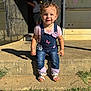 toddler, child, curly_hair, denim_overalls, pink_shirt, sandals, outdoor, sunlight, shadow, concrete_step, grass, smiling, face, person, front_yard, daylight, cute, happy, young_child, portrait