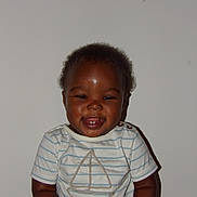 Saint joined the competition — help win amazing prizes! toddler, child, smile, teeth, striped_shirt, sailboat, short_sleeves, dark_skin, curly_hair, indoor, plain_wall, happy, sitting, portrait, cute, buttoned_shirt, baby, young_child, people, casual_clothing