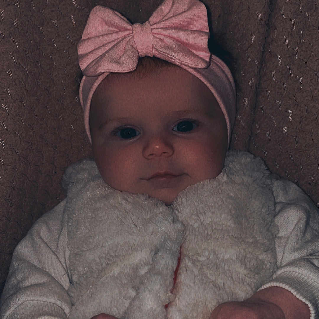 Daiana a rejoint le concours — aidez-le/la à gagner de superbes lots ! baby, background, child, clothing, cute, expression, face, hands, headband, indoor, infant, person, pink_bow, portrait, sitting, small_hands, sweet, texture, white_vest, young