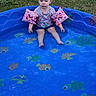 toddler, child, pool, water, floaties, pink, blue, grass, outdoor, summer, toy, fish, turtle, shirt, sitting, serious_face, car, play, kid, nature