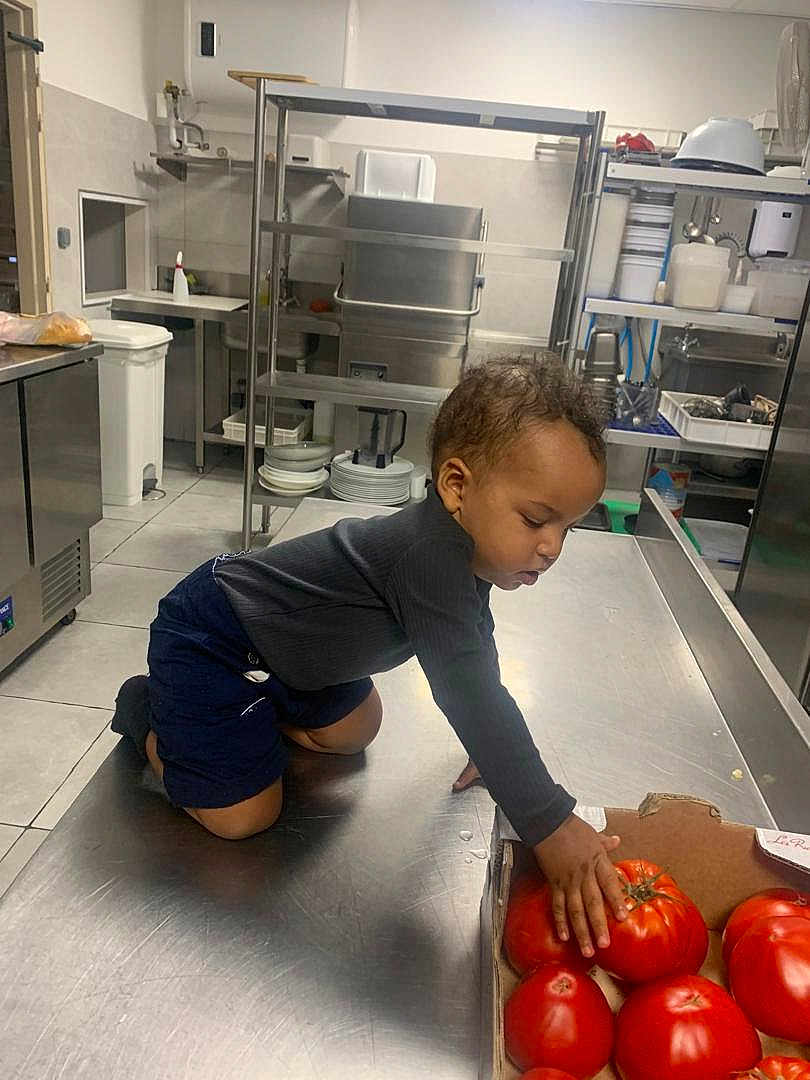 Alloux Nhesta a rejoint le concours — aidez-le/la à gagner de superbes lots ! child, clean, cooking_area, counter, crouching, curious, food, indoor, kitchen, long_sleeve, person, plates, produce, shelves, shorts, stainless_steel, toddler, tomatoes, utensils, young_child