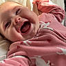 baby, infant, smiling, laughing, pink_clothing, onesie, deer_pattern, blanket, soft, cozy, happy, face, child, indoors, sunlight, cute, portrait, sleepwear, joyful, closeup