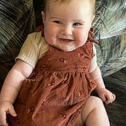 Kinsley joined the competition — help win amazing prizes! baby, barefoot, cheeks, child, couch, cute, dress, face, happy, indoors, infant, light_skin, patterned_fabric, person, plush, relaxed, short_hair, short_sleeves, sitting, smiling