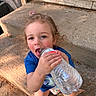 child, toddler, water_bottle, blue_shirt, concrete, steps, outdoor, curly_hair, playful, rosy_cheeks, casual_clothing, daylight, childhood, cute, person, sitting, fun, drinking, closeup, natural_light