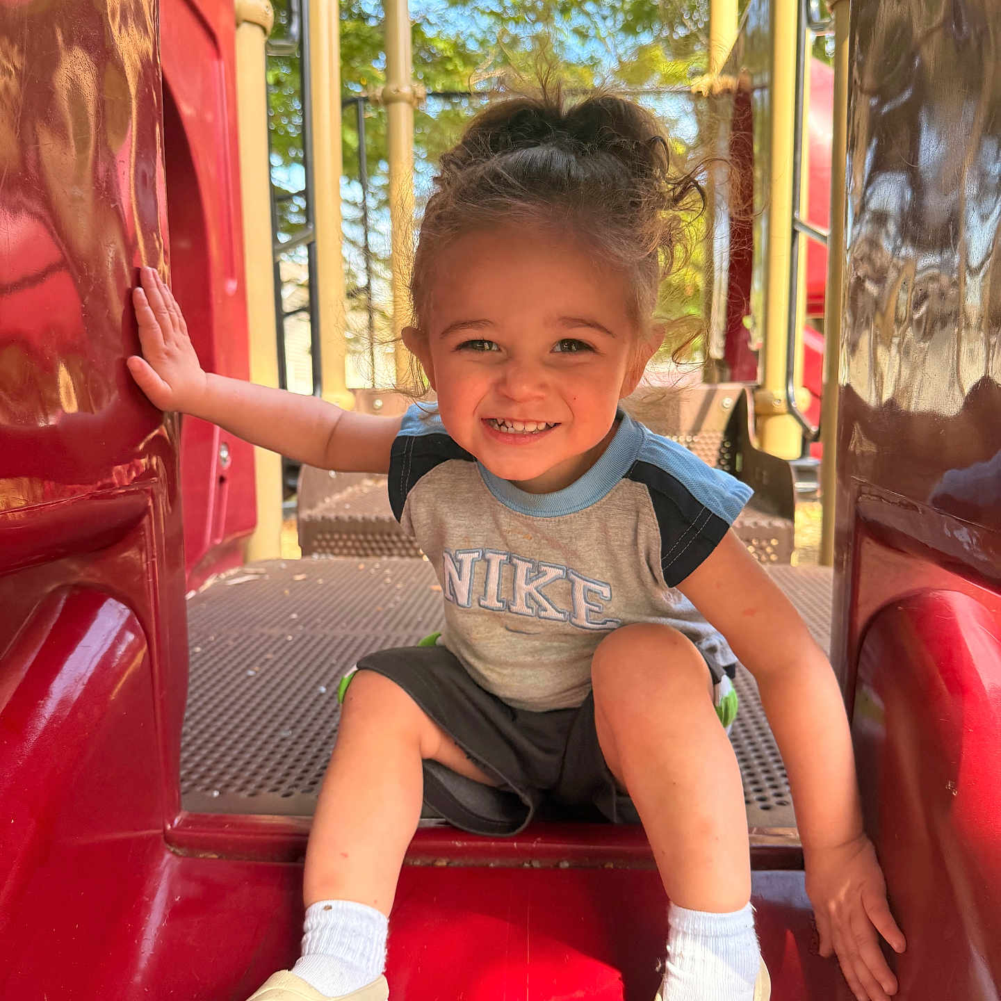 Mateo joined the competition — help win amazing prizes! toddler, child, smiling, playground, slide, red, outdoor, happy, curly_hair, sitting, clothing, socks, shoes, person, daylight, nature, fun, recreation, metal, plastic