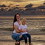 Karter joined the competition — help win amazing prizes! woman, child, beach, sunset, ocean, water, waves, clouds, sky, casual_clothing, jeans, white_shirt, barefoot, smile, family, outdoor, nature, portrait, toddler, happy