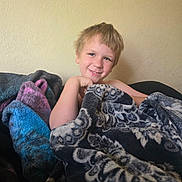 Daxton is registered to the contest to win money with this photo: blanket, blue, casual, child, comfort, cozy, face, hair, happy, home, indoor, pattern, person, portrait, purple, relaxed, smiling, texture, wall, young