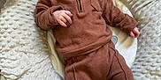 Owen is registered to the contest to win money with this photo: baby, infant, plush, cushion, brown_clothing, white_socks, face, portrait, indoor, soft_texture, cute, child, person, comfortable, lying_down, looking_at_camera, fleece, baby_clothes, cozy, expression