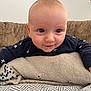 baby, infant, face, eyes, smile, blanket, couch, clothing, star_pattern, head, skin, expression, indoors, comfort, young_child, portrait, sitting, cute, soft_texture, toddler