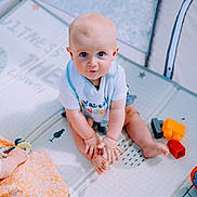 Lewenn a rejoint le concours — aidez-le/la à gagner de superbes lots ! baby, barefoot, blue_eyes, child, clothing, colorful, curious, cute, feet, floor, hands, indoor, infant, looking_up, person, plastic_toys, play_mat, sitting, soft_lighting, toys