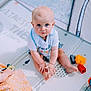 baby, barefoot, blue_eyes, child, clothing, colorful, curious, cute, feet, floor, hands, indoor, infant, looking_up, person, plastic_toys, play_mat, sitting, soft_lighting, toys
