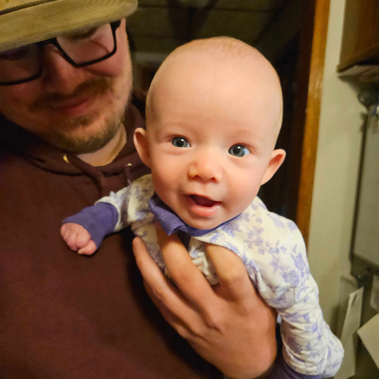 Emerie joined the competition — help win amazing prizes! baby, man, glasses, cap, smile, indoor, holding, person, face, happy, clothing, hand, headwear, portrait, family, parent, child, expression, warmth, tenderness