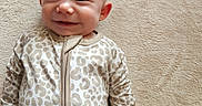 Emerie is registered to the contest to win money with this photo: baby, smiling, infant, onesie, leopard_print, soft_texture, carpet, lying_down, cute, child, happy, face, head, skin, clothing, indoors, portrait, person, comfortable, young