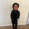 Jaleel is registered to the contest to win money with this photo: black_clothing, boy, carpet, casual_wear, child, clothing, cute, expression, footwear, happy, home, hoodie, indoor, person, portrait, smiling, standing, vent, wall, young