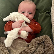 Jacob participe au concours pour gagner de l'argent avec cette photo : baby, infant, stuffed_animal, blanket, cushion, clothing, face, hand, soft_texture, comfort, indoor, cute, child, portrait, sleepwear, smiling, young, cozy, warm, resting