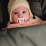 Ivy joined the competition — help win amazing prizes! baby, pacifier, knit_hat, pom_pom, blanket, pink_blanket, gray_blanket, wide_eyes, winter_clothing, cozy, infant, cute, child, face, portrait, indoors, warm, headwear, soft_texture, snug