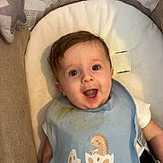 Ewen a rejoint le concours — aidez-le/la à gagner de superbes lots ! baby, infant, smiling, blue_eyes, bib, dinosaur, food_stains, cushion, star_pillow, soft_fabric, happy, cute, child, portrait, indoor, comfort, young, person, clothing, expression