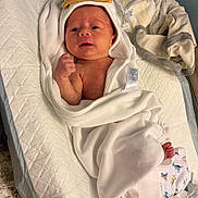Wesley is registered to the contest to win money with this photo: newborn, baby, infant, wrapped, towel, changing_pad, pacifier, diaper, clothing, hand, foot, face, expression, bedroom, baby_care, soft_texture, white, cute, hooded_towel, baby_boy