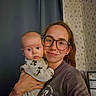 baby, infant, adult, parent, 抱抱, selfie, portrait, indoors, curtains, wallpaper, glasses, smiling, family, holding, onesie, mickey_mouse, clothing, home, photograph, faces