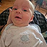 Maddox joined the competition — help win amazing prizes! adult, baby, child, close_up, curious, face, head, home, indoor, infant, lap, looking_at_camera, onesie, open_mouth, patterned_clothing, portrait, seated, smiling, white_clothing, wooden_floor