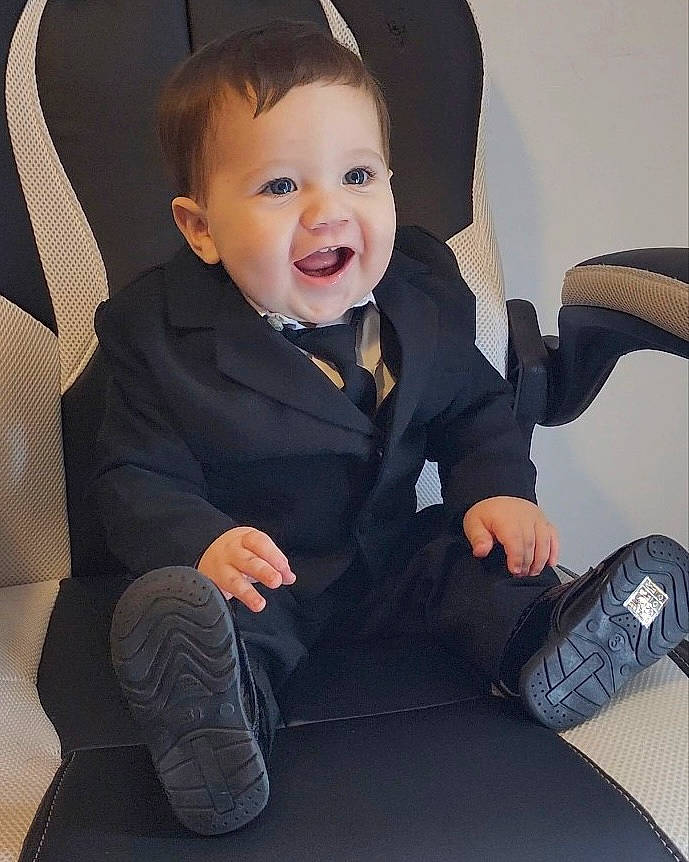 Giovanni is registered to the contest to win money with this photo: baby, baby_toddler_clothing, black, car_seat, chair, comfort, cool, electric_blue, finger, formal_wear, happy, hat, head, leg, outerwear, person, sitting, sleeve, smile, suit