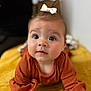 baby, child, infant, bow, orange_clothing, yellow_blanket, closeup, face, blue_eyes, curious_expression, soft_focus, indoor, portrait, cute, young_child, crawling, skin, head, person, baby_girl
