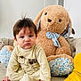 baby, child, plush_toy, stuffed_animal, bunny, couch, indoor, person, soft_toy, toddler, onesie, yellow_clothing, hand, face, fur, home, decor, seated, curious, expression
