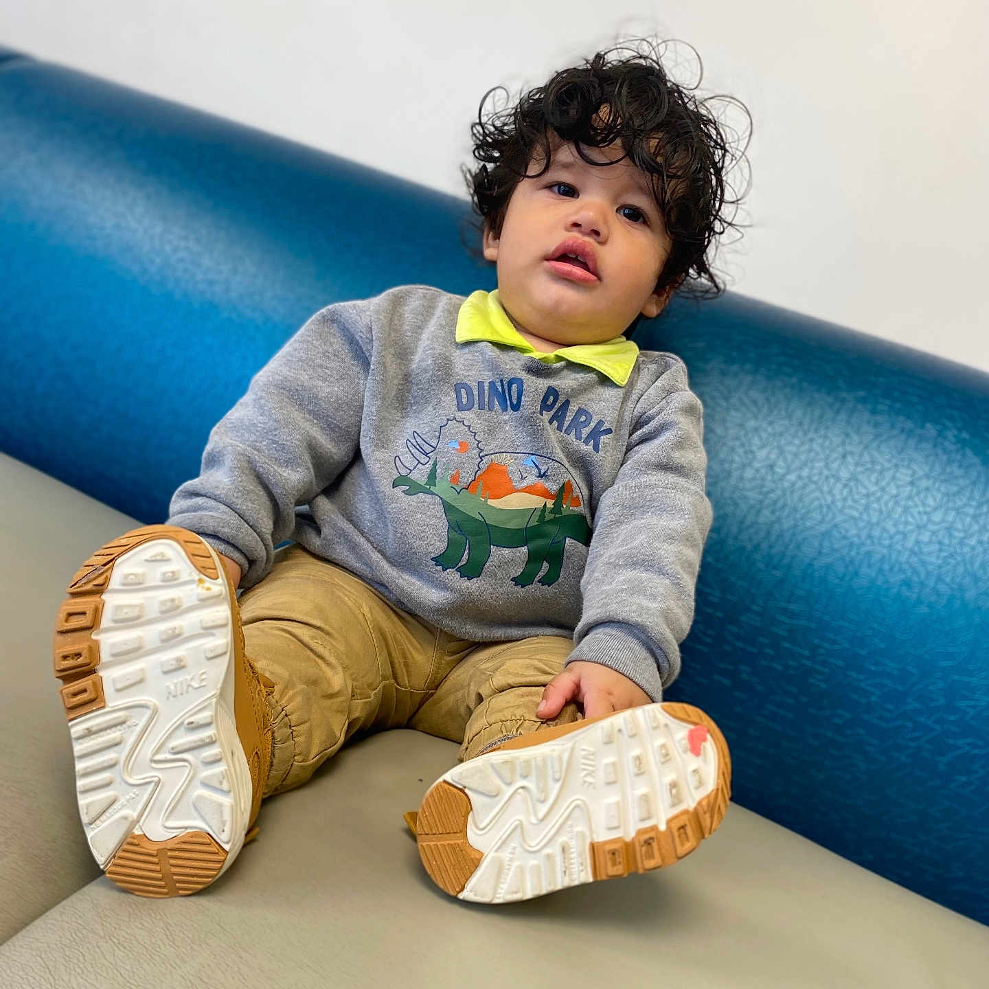 Dereck Gonzalez joined the competition — help win amazing prizes! blue, casual_clothing, child, comfortable, couch, curly_hair, cute, dinosaur, face, gray, indoor, nike, playful, portrait, shoes, sitting, smiling, sweatshirt, toddler, young_child
