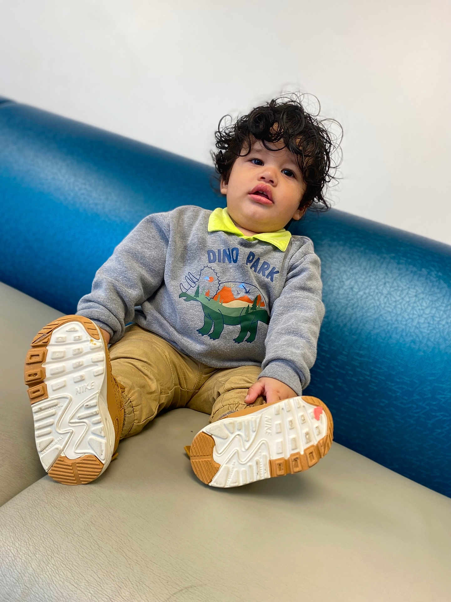 Dereck Gonzalez joined the competition — help win amazing prizes! child, toddler, curly_hair, sweatshirt, dinosaur, shoes, nike, couch, blue, gray, casual_clothing, indoor, portrait, smiling, young_child, sitting, comfortable, cute, playful, face