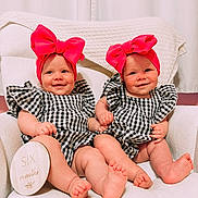 Lovelyn is registered to the contest to win money with this photo: baby, infant, twins, six_months, headband, bow, smile, holding_hands, checkered_clothing, white_chair, blanket, cute, portrait, indoors, child, feet, soft_lighting, happy, person, sitting