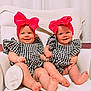 baby, infant, twins, six_months, headband, bow, smile, holding_hands, checkered_clothing, white_chair, blanket, cute, portrait, indoors, child, feet, soft_lighting, happy, person, sitting