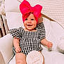 Lovelyn is registered to the contest to win money with this photo: baby, infant, child, smiling, headband, bow, checkered_dress, sitting, white_chair, milestone_sign, six_months, cute, happy, indoor, plush, portrait, person, skin, hand, leg