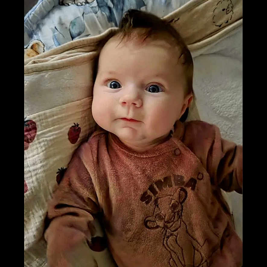 Mia a rejoint le concours — aidez-le/la à gagner de superbes lots ! baby, blanket, brown, child, clothing, curious, cute, expression, eyes, face, indoor, infant, lying_down, patterned_blanket, pink, portrait, simba, soft_toys, warm, young_child