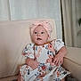 Louna a rejoint le concours — aidez-le/la à gagner de superbes lots ! baby, child, girl, headwrap, pink, floral_dress, couch, indoor, curtains, blanket, sitting, cute, portrait, smiling, happy, soft_light, home, comfort, hands, face